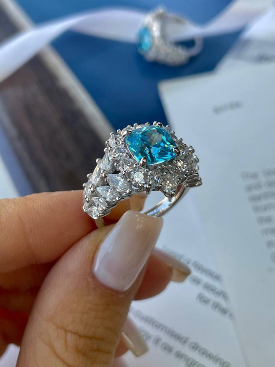 نمای نزدیک انگشتر نقره زنانه با نگین آبی اقیانوسی بر روی انگشت با آبکاری رادیوم درخشان