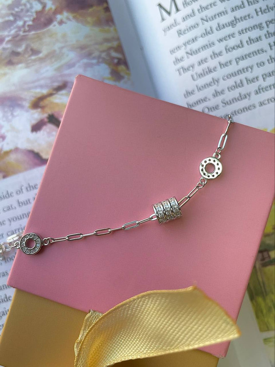 نمای دستبند نقره ۳.۲ گرمی طرح دخترانه روی مچ دست در کنار کتاب