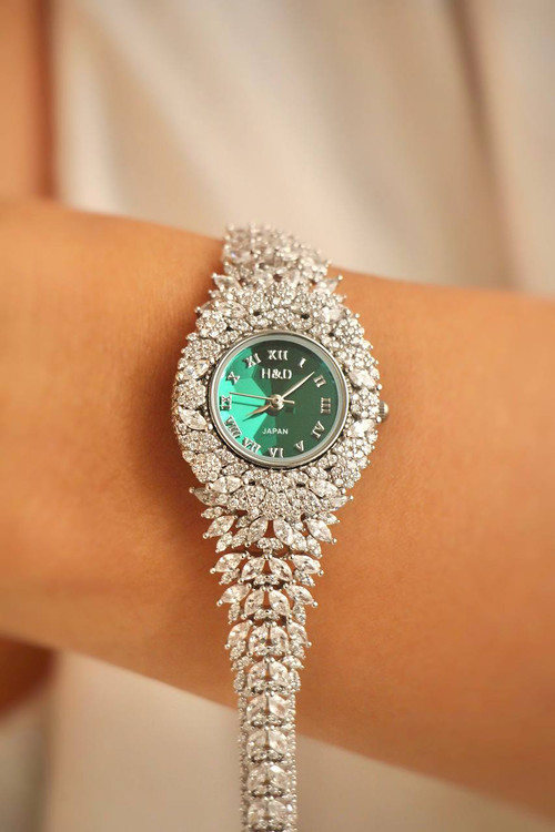 نمای نزدیک ساعت نقره زنانه مدل زمردین با صفحه سبز روی مچ دست.