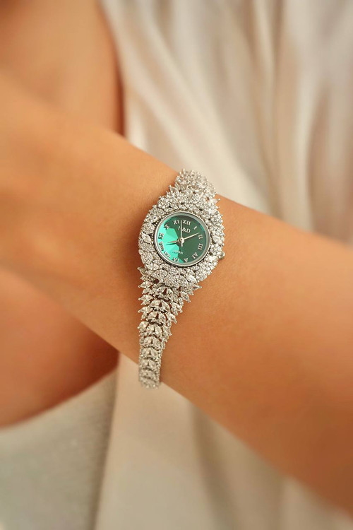 نمای نزدیک ساعت نقره زنانه مدل زمردین با صفحه سبز روی مچ دست.