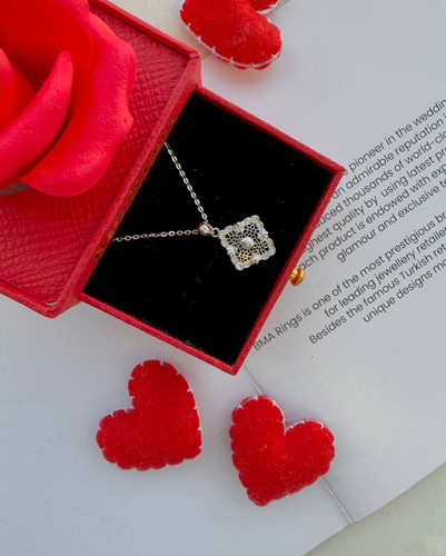 نمای نزدیک گردنبند نقره طرح مشبک اسلیمی روی زمینه قرم