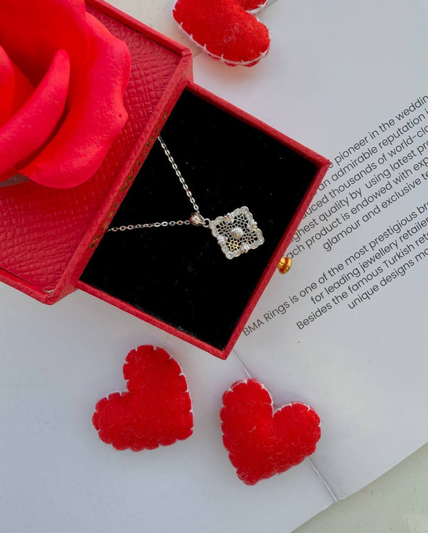 نمای نزدیک گردنبند نقره طرح مشبک اسلیمی روی زمینه قرم