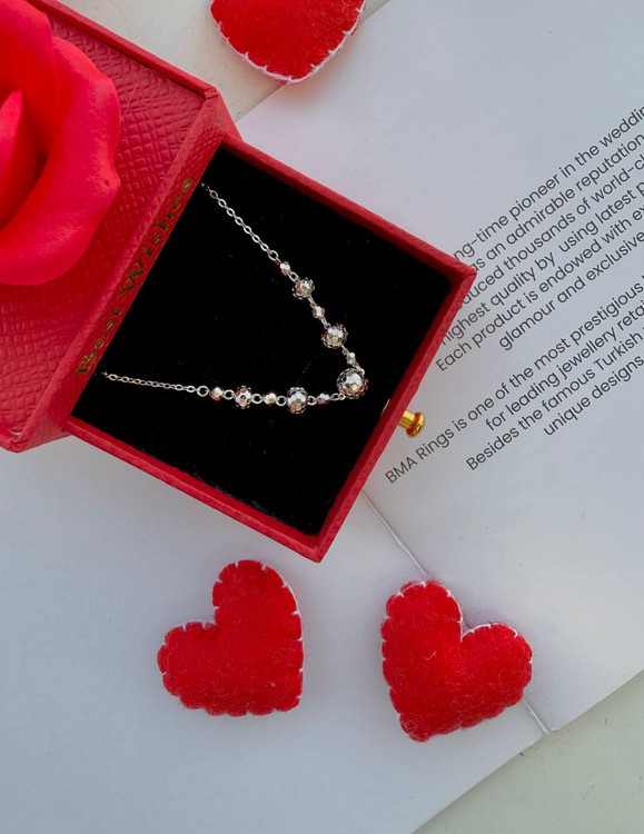 گردنبند نقره البرنادو ایتالیایی با گویهای درخشان در جعبه قرمز در کنار دو قلب تزئینی.
